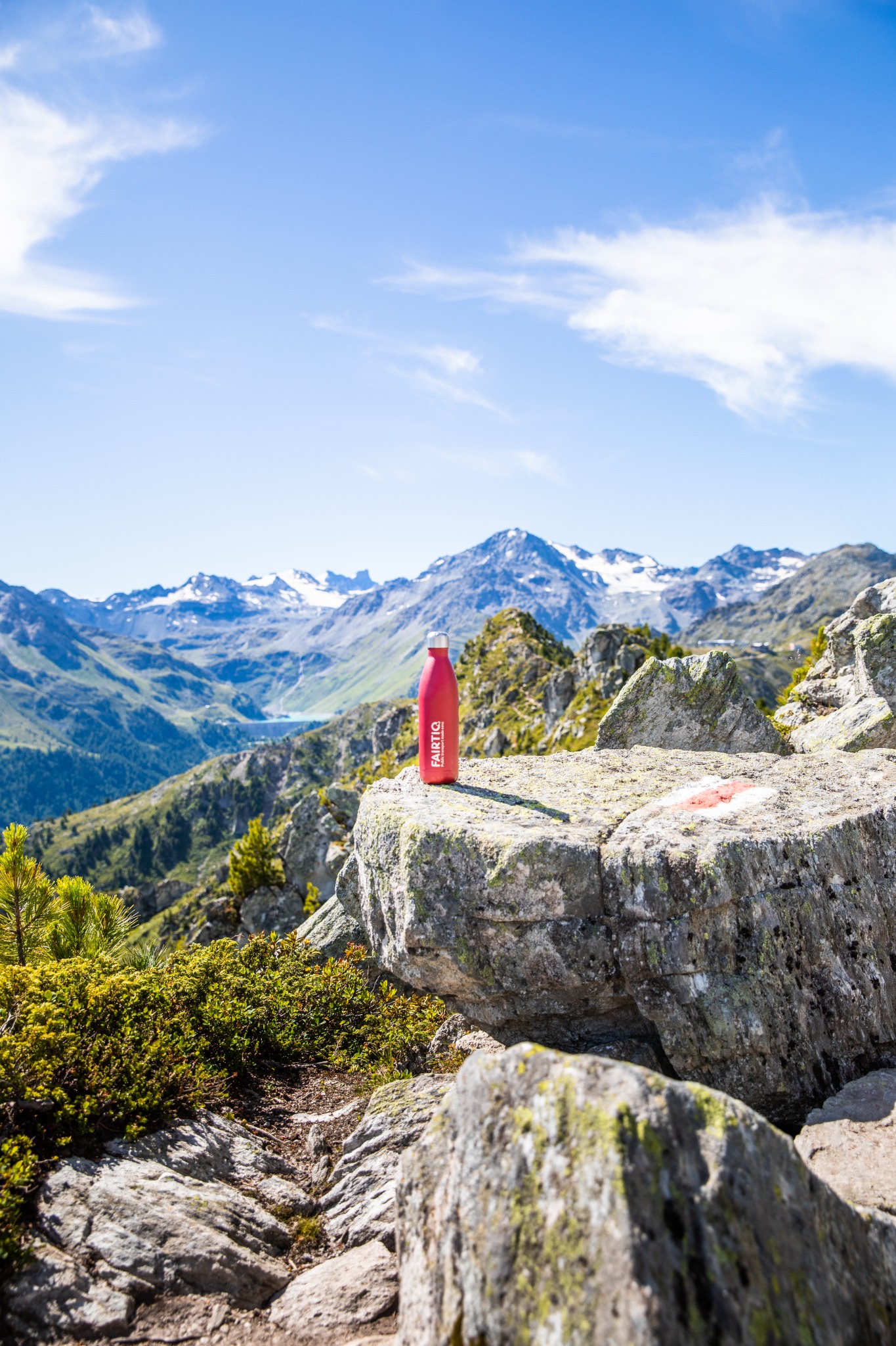 Mountain landscape with a red FAIRTIQ bottle on a rock